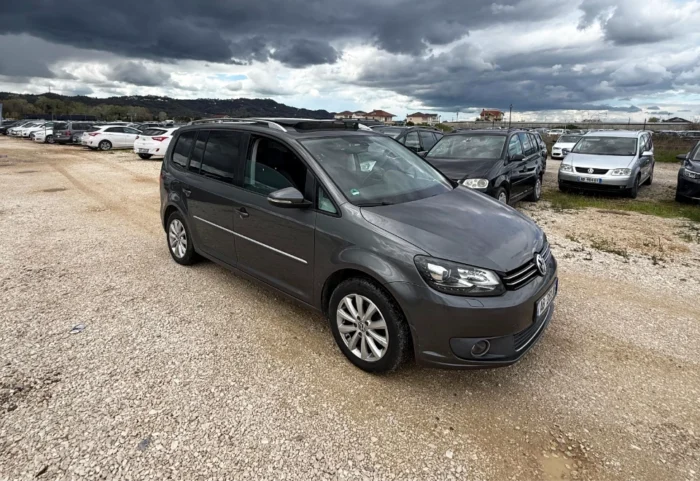 Front three-quarter view of gray VW Touran 2013 2.0 TDI diesel automatic 7-seater rental with panoramic sunroof parked in Albania