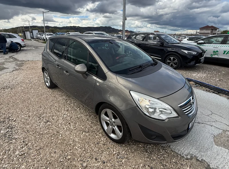 Opel Meriva 2012 - 2.0 Diesel Manual 7 Seater with Panoramic Sunroof Rental in Tirana Albania 1 - Car Rent in Albania Grey Opel Meriva 2012 2.0 diesel manual compact MPV with panoramic sunroof and dark interior parked near Tirana International Airport Rinas
