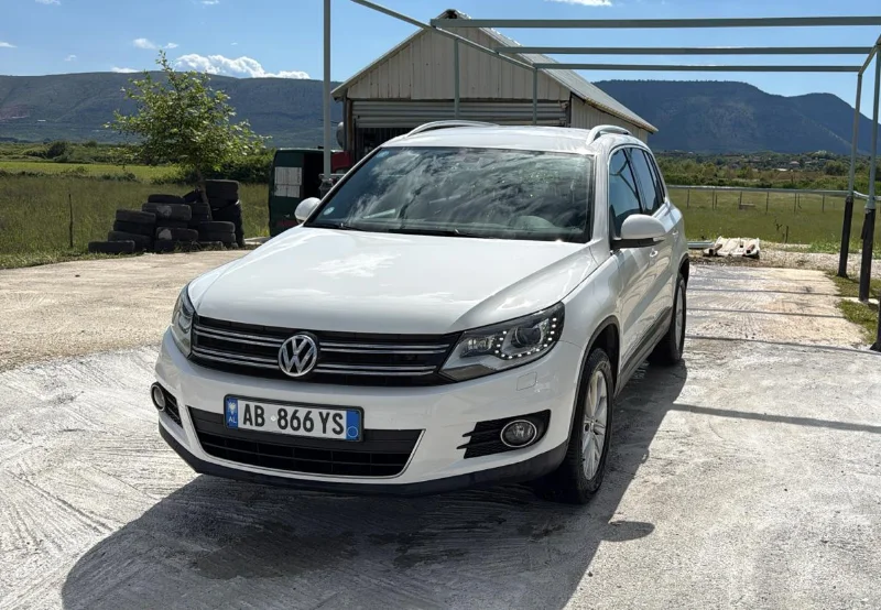 Volkswagen Tiguan 2014 - 2.0 TDI Diesel Automatic 4x4 SUV Rental in Tirana Albania 1 - Car Rent in Albania White Volkswagen Tiguan 2014 2.0 TDI diesel automatic 4x4 SUV parked in the Albanian countryside, available for rental from Tirana and Tirana Airport Rinas